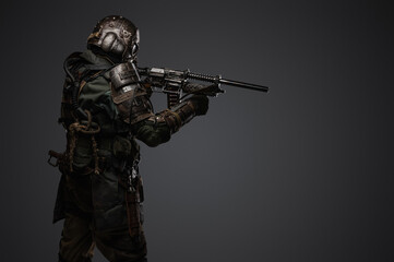 Portrait of military man in post apocalypse style dressed in armored suit aiming shotgun.