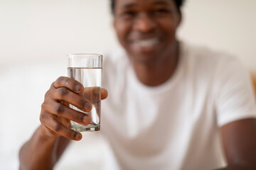 Smiling Young Black Guy Giving Glass With Mineral Water At Camera