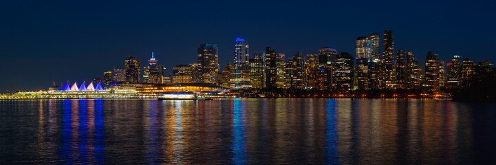 Fototapeta na wymiar Vancouver metropolitan skyline, buildings, and water reflections in blue, gold, and orange colors on Vancouver Harbor, night view of the city