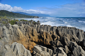 pancake rock or geological pattern of cliff at coast of new zealand with blue sky, sea and...