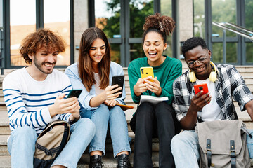 Happy University student friends having fun sharing good times on online phone app sitting on the...