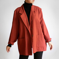 Woman wearing oversized red blazer, black turtleneck and black jeans isolated on white background
