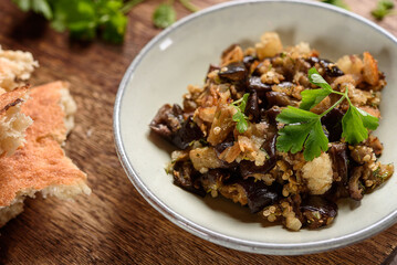 Fried chopped eggplant with garlic and bread crumbs in a bowl on wooden table. Vegetable gourmet snack or appetizer. Selective focus - 546585912