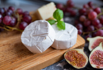 delicious blue brie blue cheese with grapes and figs on a wooden board