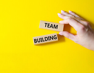 Team Building symbol. Concept word Team Building on wooden blocks. Businessman hand. Beautiful yellow background. Business and Team Building concept. Copy space