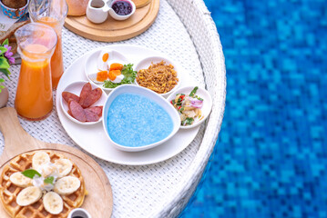Breakfast in swimming pool, floating breakfast in villa resort. relaxing in calm pool water, healthy breakfast and tropical fruit.