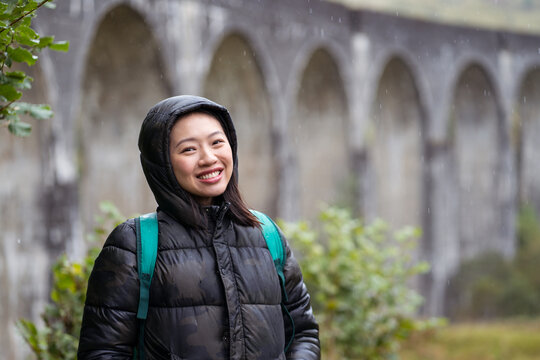 Smiling Asian female in warm jacket standing on street