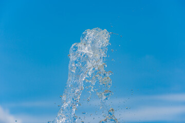 Clear transparent water splash against blue sky with a few clouds