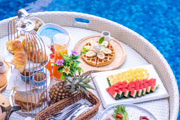 Breakfast in swimming pool, floating breakfast in villa resort. relaxing in calm pool water, healthy breakfast and tropical fruit.
