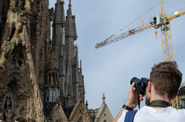 Photographer man taking a photo with his camera focusing the sagrada familia in Barcelona.
Man...