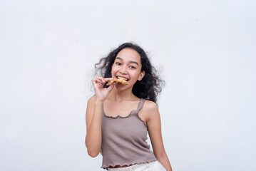 A young asian woman looking at the camera before taking a bite of a sweet chili chicken wing. Isolated on a light background.