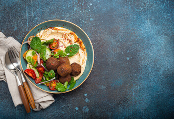 Middle Eastern Arab meal with fried falafel, hummus, vegetables salad with fresh green cilantro and mint leaves in ceramic bowl on stone rustic background top view. Arabic cuisine, space for text © somegirl