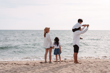Happy asian family on the beach in holiday. of the family holding hands, Son and daughter piggyback on parents.They are having fun playing enjoying on the beach. Summer Family and lifestyle concept.
