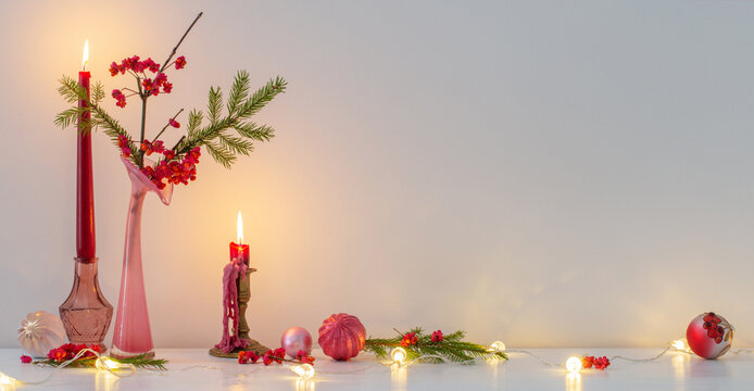 pink christmas decor with burning candles in white interior