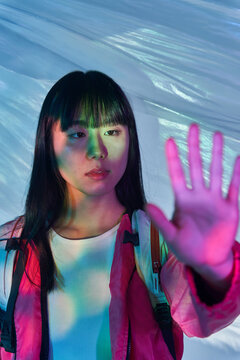 Asian woman showing stop gesture in futuristic light