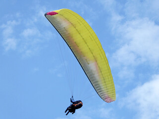 Yellow tandem Paraglider flying in a blue sky	