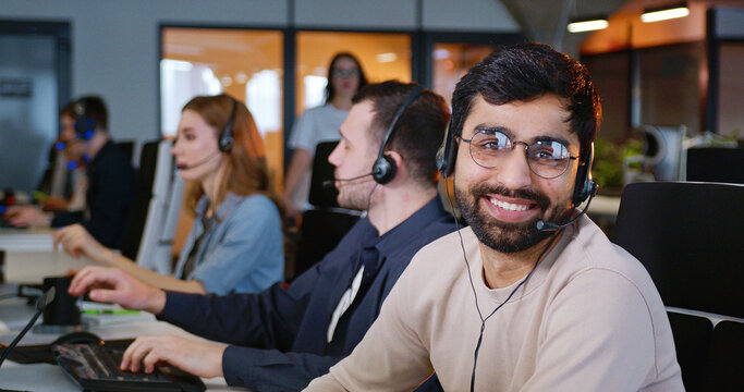 Call center. Portrait of happy male support worker in office looking at camera and smiling.