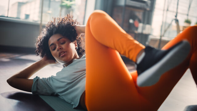 Black Athletic Fit Female Doing Crisscross Crunch Exercises at Home in Her Sunny Living Room. Woman Doing Workout Fitness, Abdominal Exercises. Beautiful Cinematic Shot of Attractive Person.