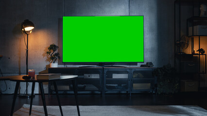 Stylish Loft Apartment Interior with TV Set with Green Screen Mock Up Display Standing on...