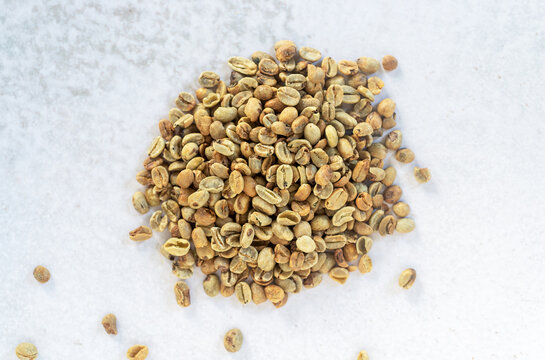 a pile of green bean coffee defect on marble background