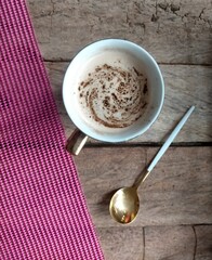 cup of coffee and spoon on wood and pink background 