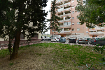 Facades of residential houses of light brown exposed brick with lawn gardens and trees