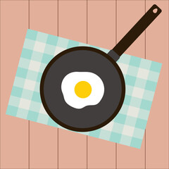 Simple flat tasty morning breaksfast on a black pan, blue napkin and brown wooden table consist of one fried egg 