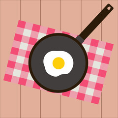 Simple flat tasty morning breaksfast on a black pan, red napkin and brown wooden table consist of one fried egg 