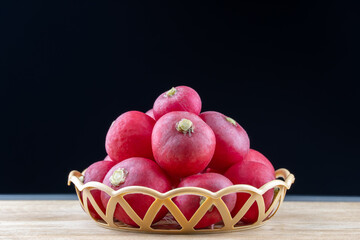 Still life organic ripe radish fresh vegetable in wicker basket on wooden background. Raw diet lifestyle. Heap raphanus sativus family brassicaceae on black background. Healthy nutrition organic food.