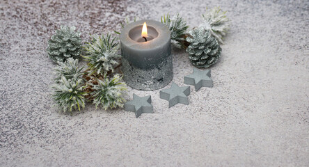 Graue Weihnachtskerze mit Sternen und Zweigen.