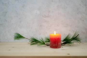 Red candle lit for the first Advent, pine branch as a simple, minimal decoration on a light wooden...