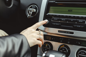 Woman turns on media radio in a car