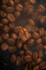 Fototapeta premium Roasting coffee with smoke. Macro photography of coffee beans on the background of coffee with steam. Flying coffee bean.