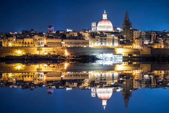 View of harbor and Valletta old town at night with reflection in water. Night Valletta. City center.