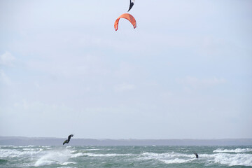 Kitesurfing, riding board waves during storm holding to flying kite.