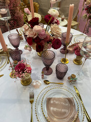 Festive table setting in pink purple red style with candles and flowers.