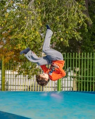 Foto op Plexiglas healthy sport little caucasian boy jumping somersault outdoors nature with copyspace © PapatoniC