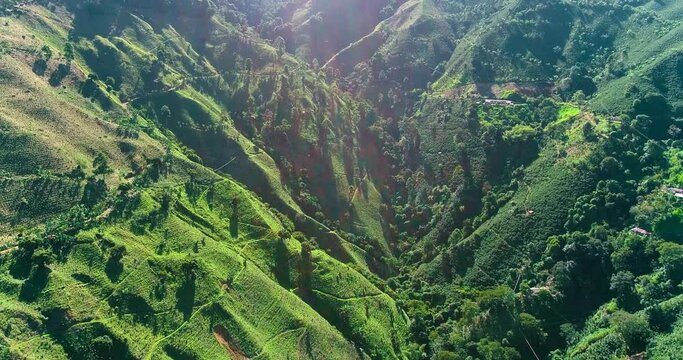 Drone view of two green mountains with a narrow valley linking them.