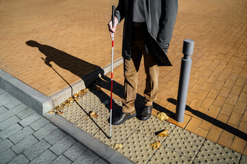 Close-up of a blind man with a walking stick. Detects tactile tiles for self-orientation while moving through the streets of the city