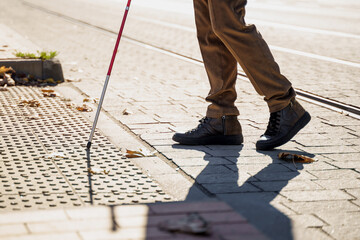 Close-up of a blind man with a walking stick. Detects tactile tiles for self-orientation while moving through the streets of the city