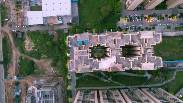 straight down aerial drone shot showing high rise skyscraper buildings with cricket ground and pool in a high end society in gurgaon, delhi, mumbai India showing real estate housing