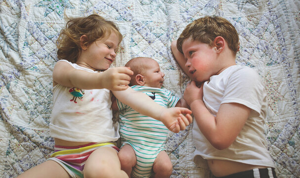 High angle view of siblings lying on bed at home
