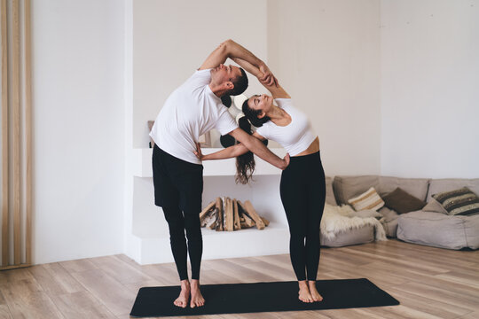 Multiethnic couple stretching in yoga position in living room