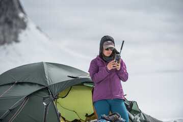 A woman uses a satellite phone outside a tent on a glacier in Denali National Park.
