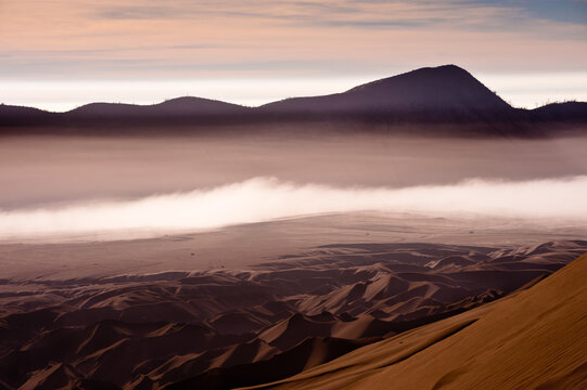 Sand dunes with clouds and layers of fog.