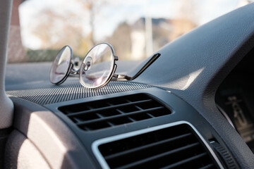 Glasses on the dashboard of a car. Accessory for drivers with vision problems. Road safety concept.