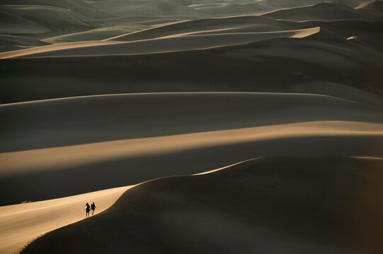 A young couple hiking through sand dunes at sunset