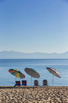 Sun umbrellas and beach chairs in a row at Lake Tahoe.