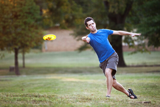 A man makes a forehanded throw playing disc golf.