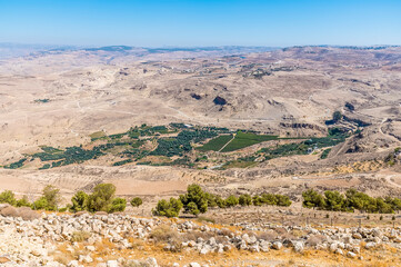 A view down the slopes of Mount Nebo, Jordan towards an oasis below in summertime